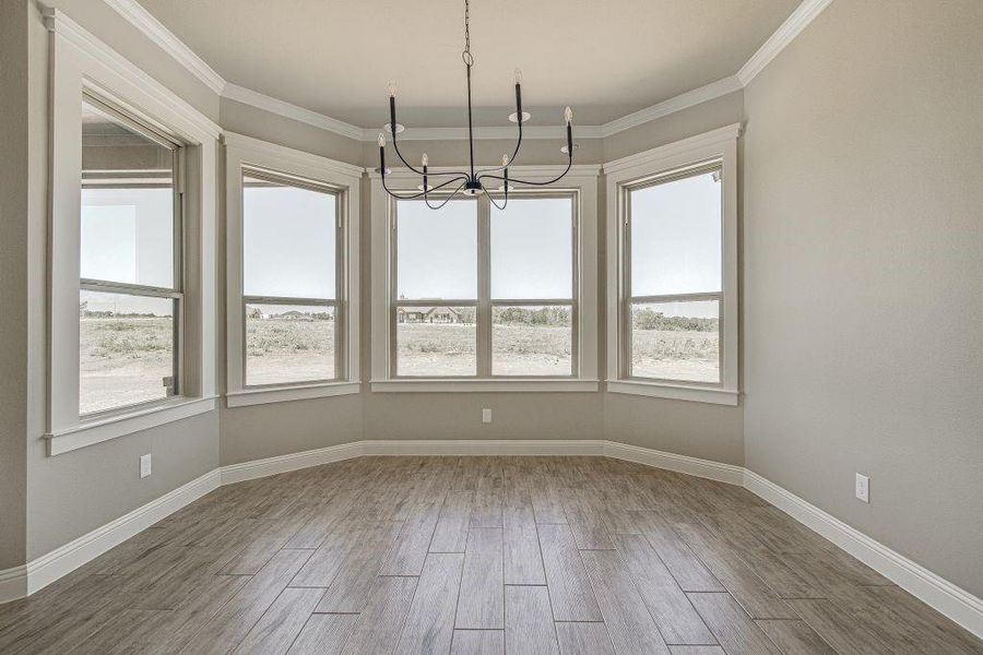 Unfurnished dining area featuring crown molding, a chandelier, and hardwood / wood-style floors