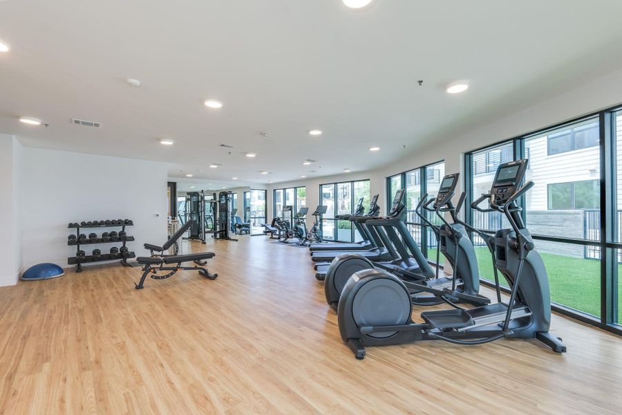 The fitness center offers a variety of exercise equipment including treadmills, elliptical machines, and free weights, all set on a light wood-look floor