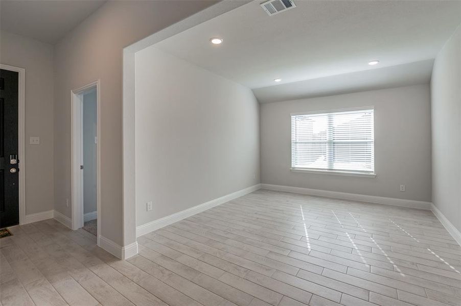 Open concept interior featuring light-toned wood-finish flooring, recessed ceiling lighting, and a window with horizontal blinds