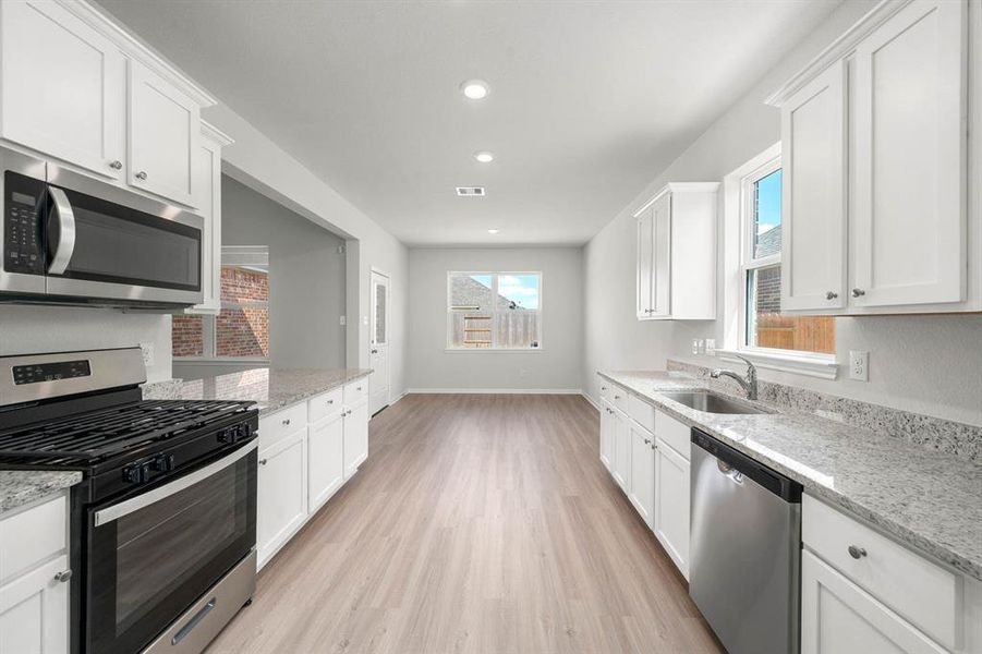 Sprawling granite counters provide a beautiful workspace to prepare food and plenty of room to display stylish knick-knacks and gadgets.