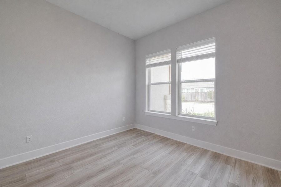 This room features light-colored walls, wood-style flooring, and two windows with blinds