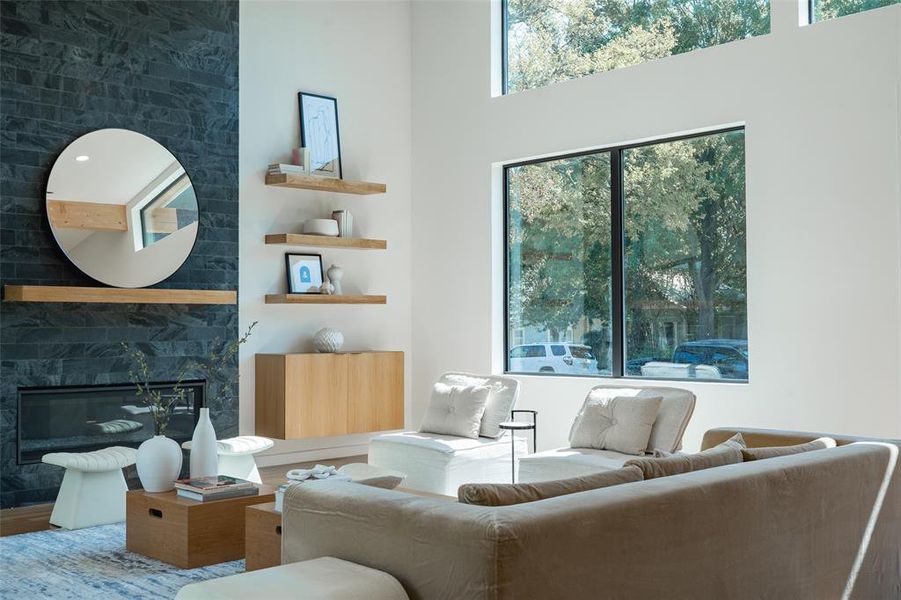 Living room with a towering ceiling, a high end fireplace, and hardwood / wood-style floors