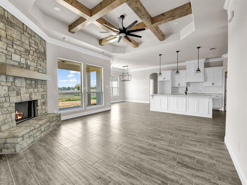 Unfurnished living room with a stone fireplace, baseboards, ceiling fan, and wood tiled floor Unfurnished living room with a stone fireplace, baseboards, ceiling fan, and wood tiled floor
