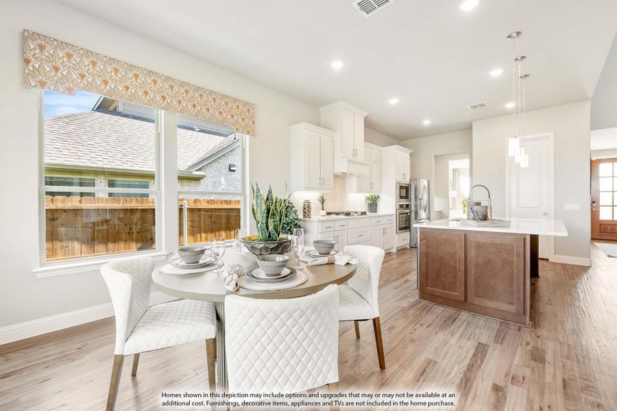 Open dining area with round table flowing into kitchen with white cabinets, wood island, and hardwood floors Open dining area with round table flowing into kitchen with white cabinets, wood island, and hardwood floors