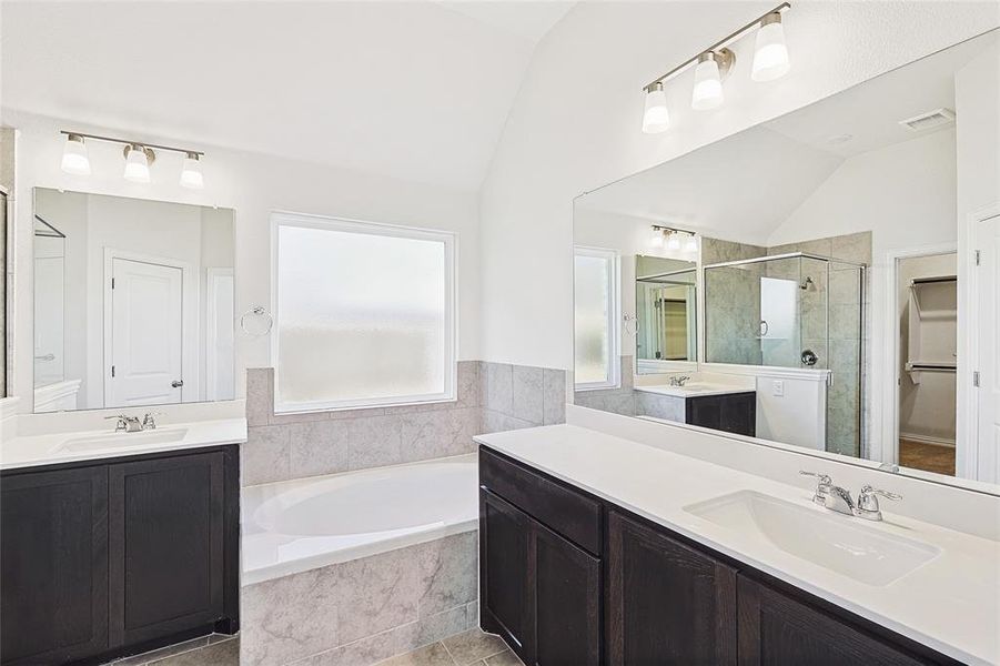 Bathroom with tile patterned floors, vanity, plus walk in shower, and lofted ceiling