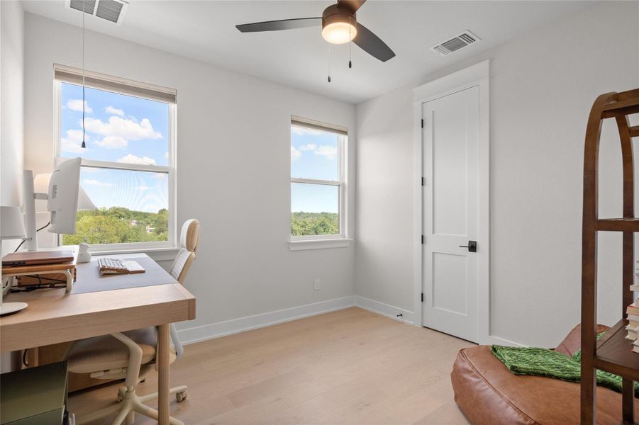 A quiet retreat with blonde wood flooring, tall windows, and a functional overhead fan for comfortable living. A quiet retreat with blonde wood flooring, tall windows, and a functional overhead fan for comfortable living.