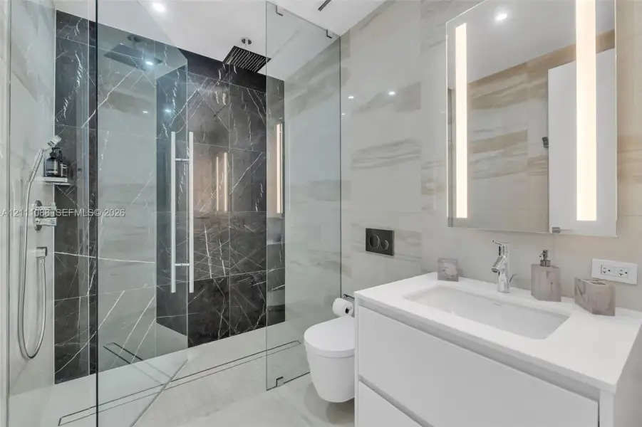 Walk-in shower featuring glass enclosure, rain-style showerhead, and dual-toned tile surround Walk-in shower featuring glass enclosure, rain-style showerhead, and dual-toned tile surround