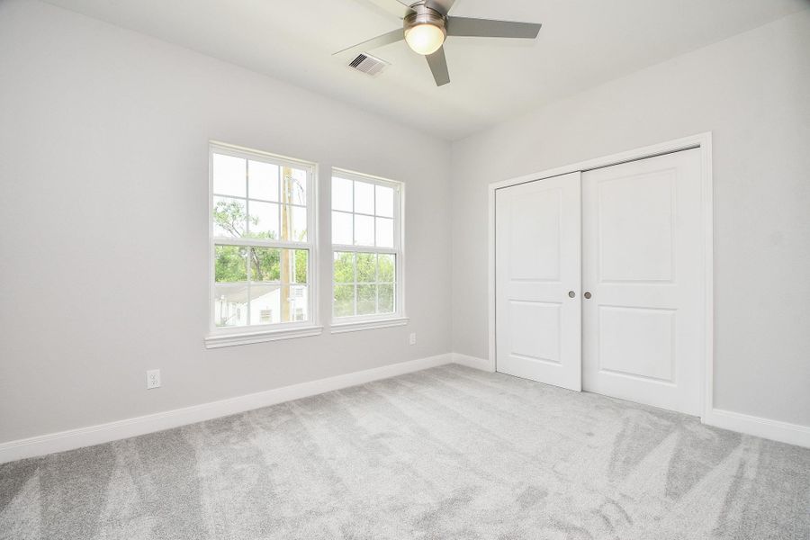 Step into a bright and spacious third bedroom featuring a walk-in closet and a ceiling fan, perfect for comfort and style.