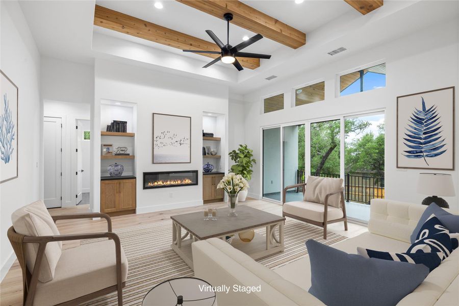 Living area featuring an electric glass covered fireplace, engineered white oak wood floors and beamed ceiling. Virtually staged. Living area featuring an electric glass covered fireplace, engineered white oak wood floors and beamed ceiling. Virtually staged.