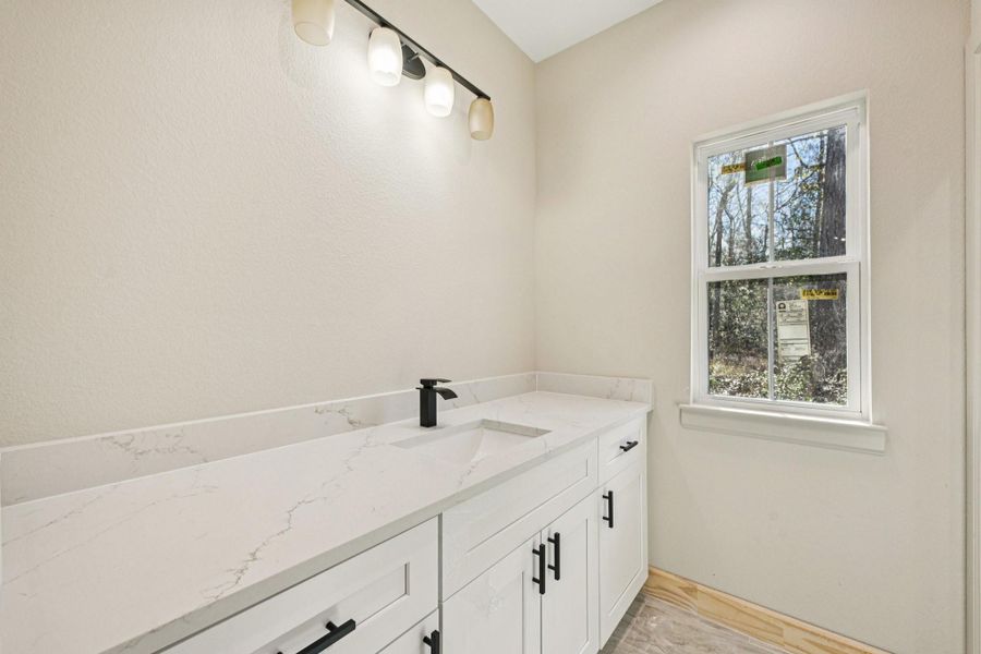 This bathroom features a sleek design with  quartz countertop, modern black fixtures.