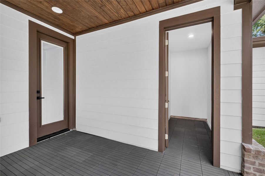 Charming entryway with a modern wood-paneled ceiling and sleek dark flooring, complemented by crisp white walls and rich brown trim for a welcoming entrance. additional storage room