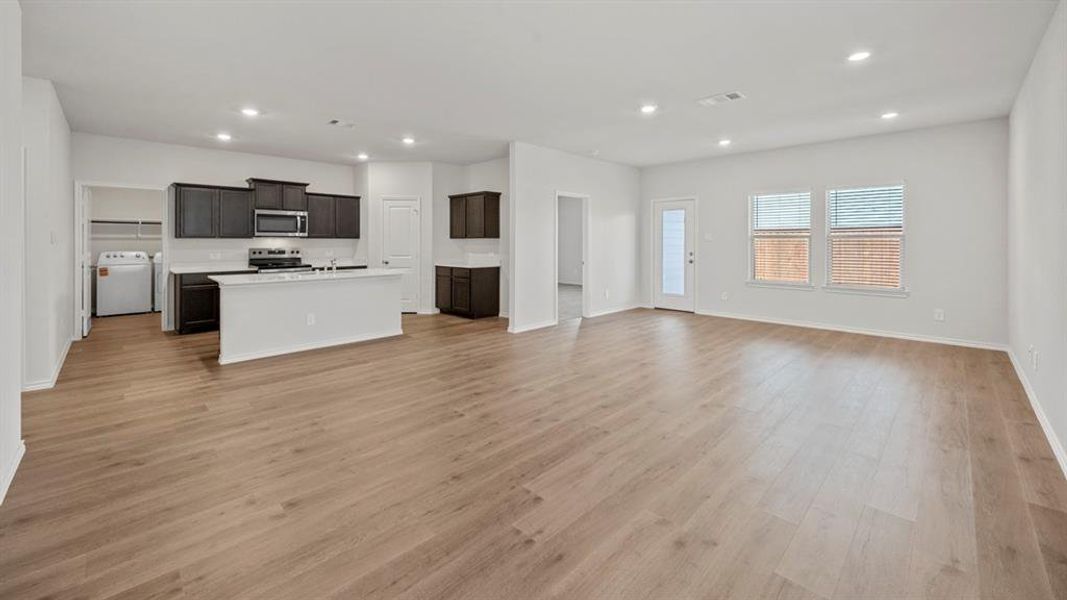 Kitchen with open floor plan, recessed lighting, a center island with sink, washer / dryer, and stainless steel appliances