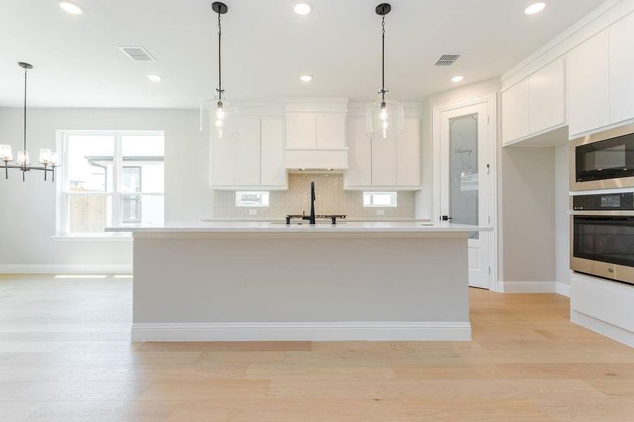 Kitchen featuring light hardwood / wood-style flooring, tasteful backsplash, stainless steel appliances, pendant lighting, and sink