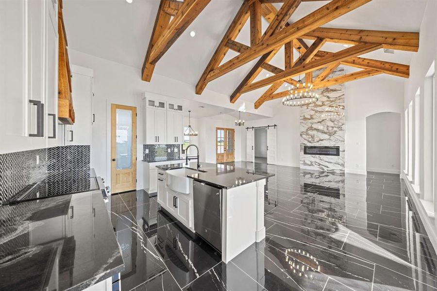 Kitchen featuring high vaulted ceiling, a sink, a chandelier, arched walkways, and white cabinetry Kitchen featuring high vaulted ceiling, a sink, a chandelier, arched walkways, and white cabinetry