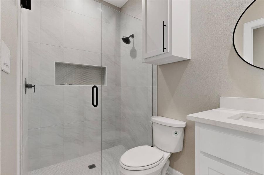 Full bathroom featuring vanity, a textured wall, and a shower stall Full bathroom featuring vanity, a textured wall, and a shower stall