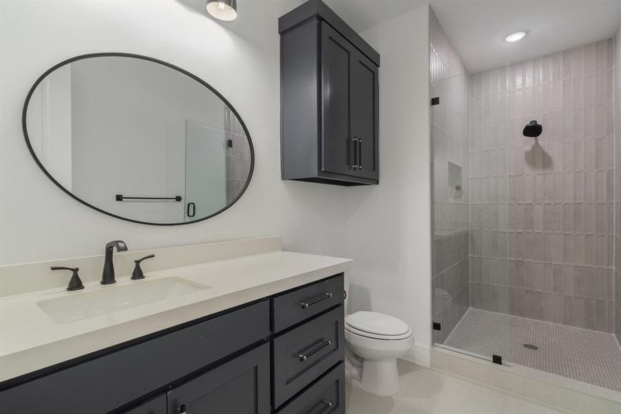 Bathroom featuring vanity, toilet, and a tile shower