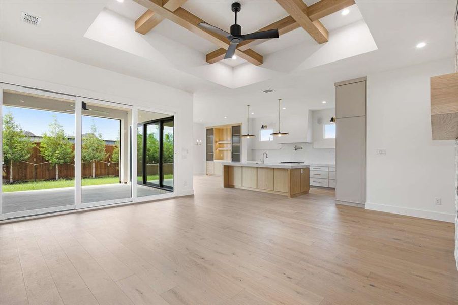 Unfurnished living room featuring beamed ceiling, ceiling fan, and light hardwood / wood-style flooring