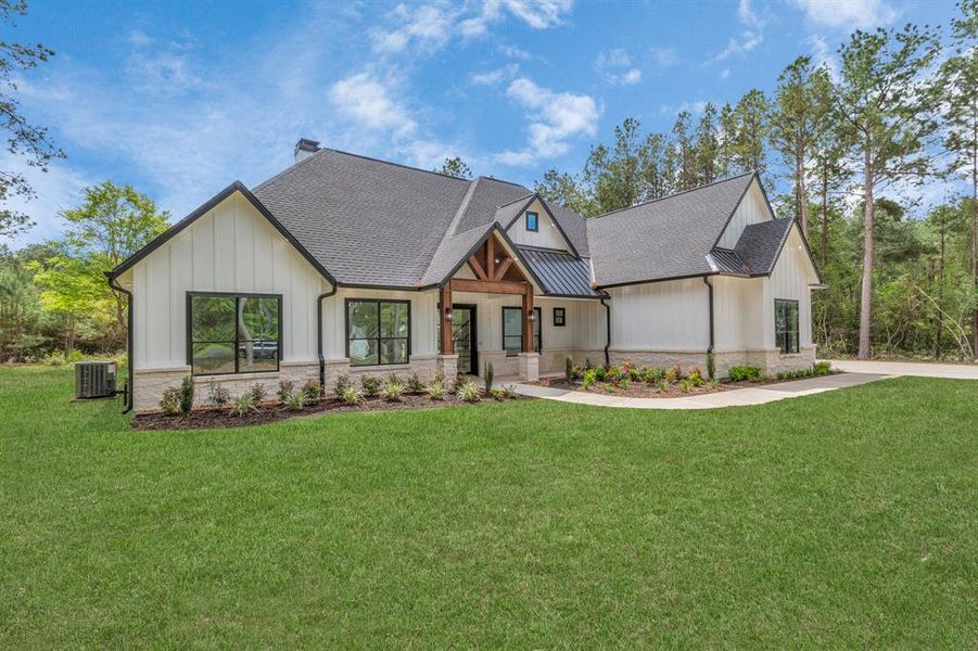 A fresh landscaping design, expansive windows, a mix of gabled roofs, and an inviting entryway with wood accents.