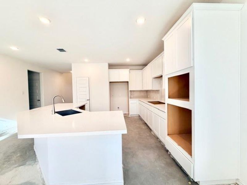 Kitchen featuring white cabinets, an island with sink, concrete floors, recessed lighting, and backsplash