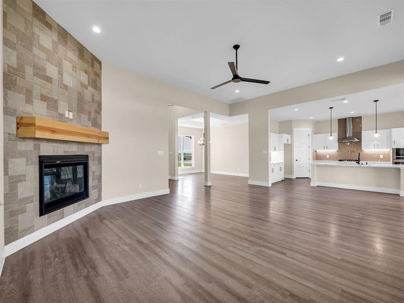 Unfurnished living room with sink, dark hardwood / wood-style floors, a tile fireplace, and ceiling fan