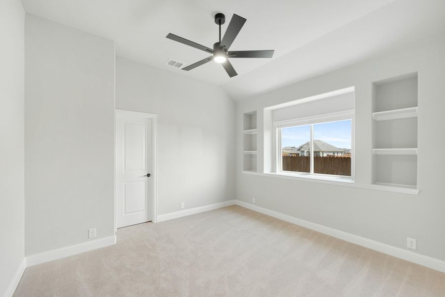 Empty bedroom with carpet, ceiling fan, built-in shelves flanking a window, and vaulted ceiling Empty bedroom with carpet, ceiling fan, built-in shelves flanking a window, and vaulted ceiling