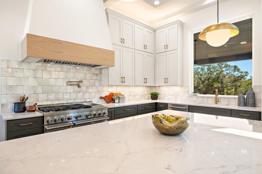 Kitchen with decorative backsplash, custom range hood, light stone countertops, stainless steel appliances, and a sink