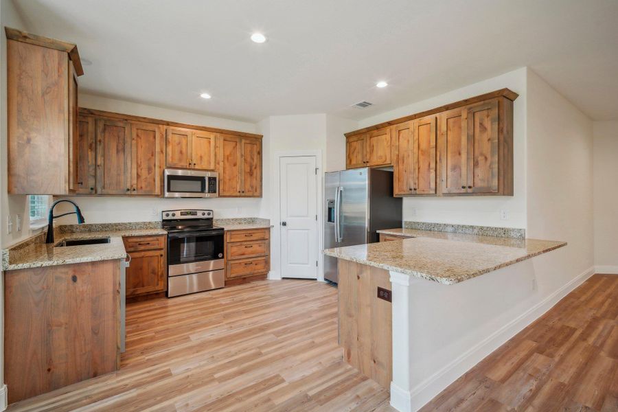 Kitchen with visible vents, a sink, stainless steel appliances, a peninsula, and light wood finished floors