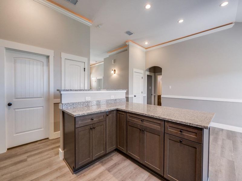 Kitchen featuring light wood-type flooring, visible vents, arched walkways, and crown molding
