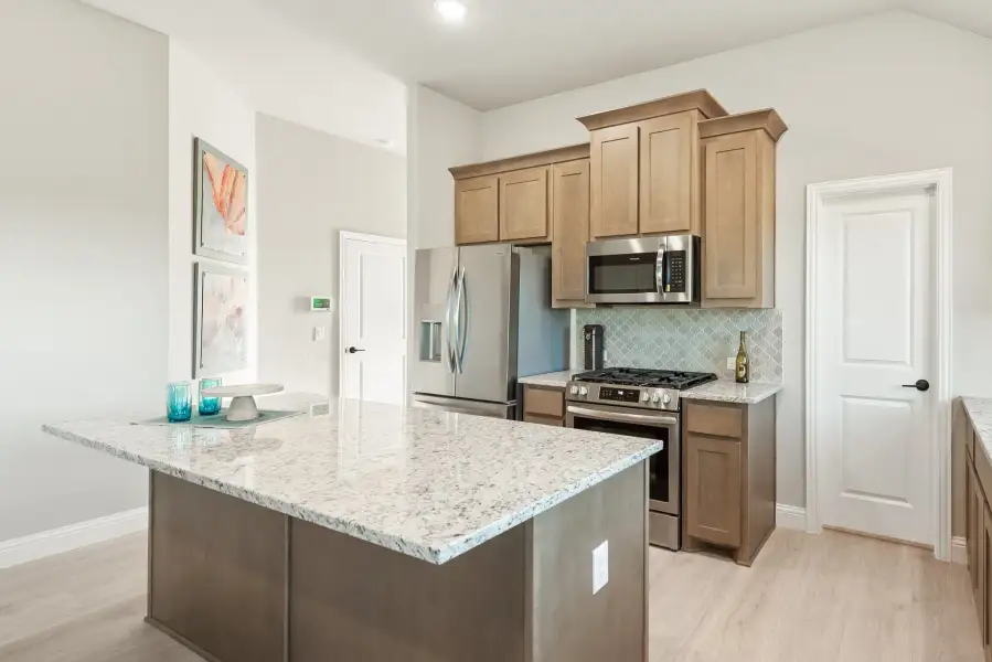 Kitchen with granite island, tan cabinets, stainless steel appliances, and tiled backsplash Kitchen with granite island, tan cabinets, stainless steel appliances, and tiled backsplash