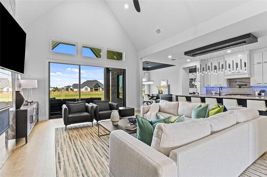 Living room with high vaulted ceiling, light wood-style flooring, recessed lighting, and a ceiling fan