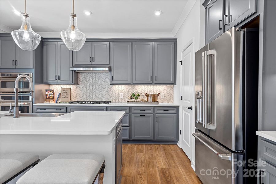 Rich grey cabinetry and quartz countertops paired with modern backsplash.