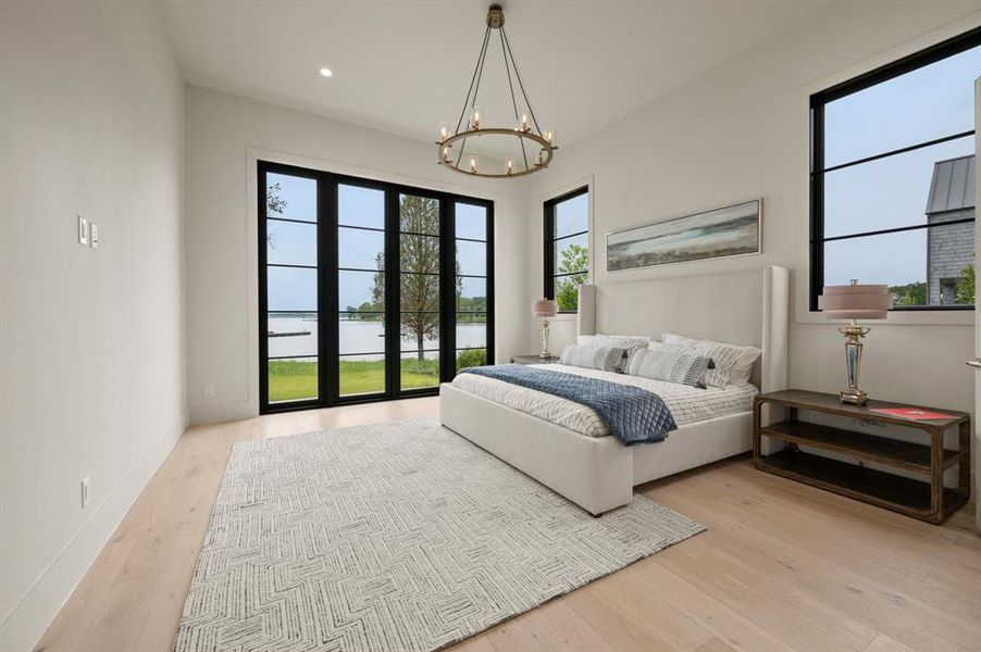 Bedroom with wood finished floors, a chandelier, a water view, recessed lighting, and baseboards Bedroom with wood finished floors, a chandelier, a water view, recessed lighting, and baseboards