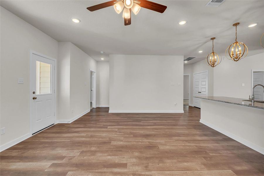 Unfurnished living room featuring recessed lighting, light wood-style flooring, ceiling fan, and a chandelier Unfurnished living room featuring recessed lighting, light wood-style flooring, ceiling fan, and a chandelier