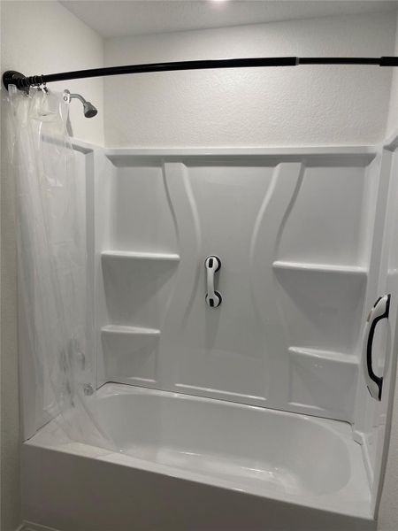 Full bathroom with a textured wall and shower / bath combo with shower curtain
