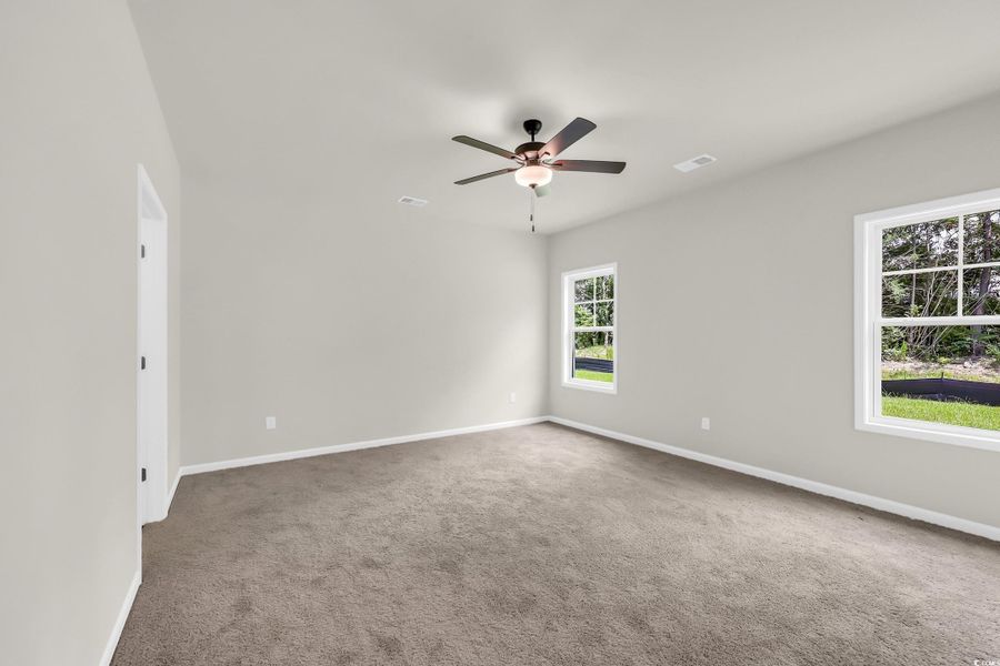 Unfurnished room featuring light carpet and a ceiling fan