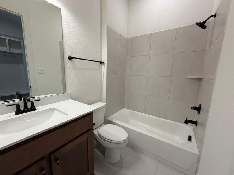 Full bathroom with vanity, bathing tub / shower combination, a textured wall, and light tile patterned floors