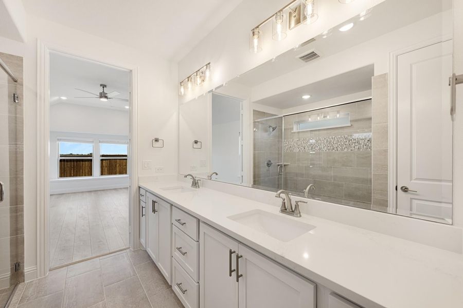 Master bathroom with double vanity, white quartz countertops, large mirror, and glass-enclosed tile shower. Master bathroom with double vanity, white quartz countertops, large mirror, and glass-enclosed tile shower.