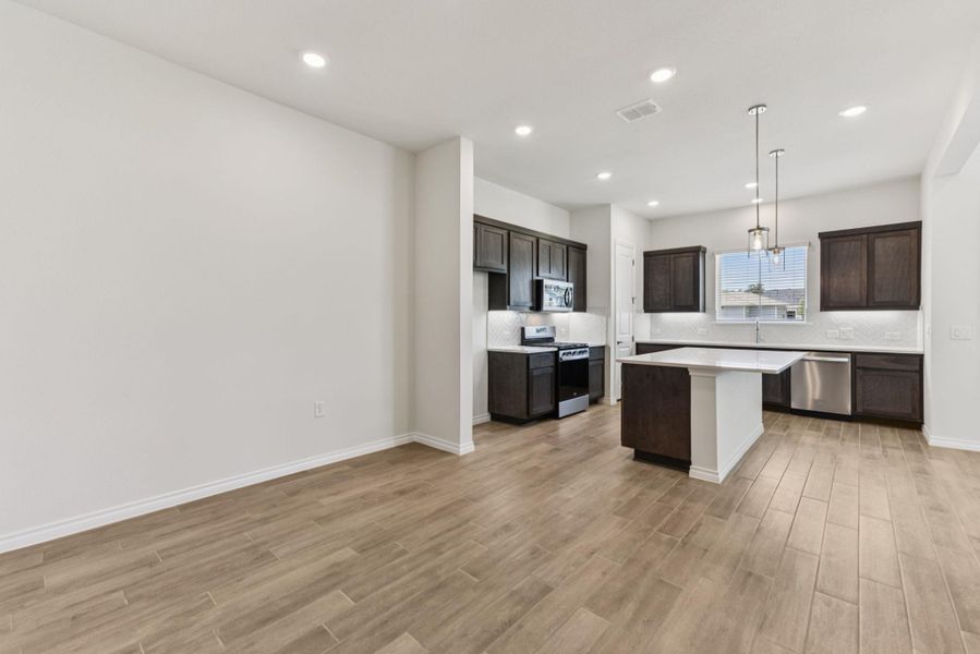 Kitchen featuring decorative backsplash, stainless steel appliances, dark brown cabinetry, a kitchen island, and recessed lighting Kitchen featuring decorative backsplash, stainless steel appliances, dark brown cabinetry, a kitchen island, and recessed lighting
