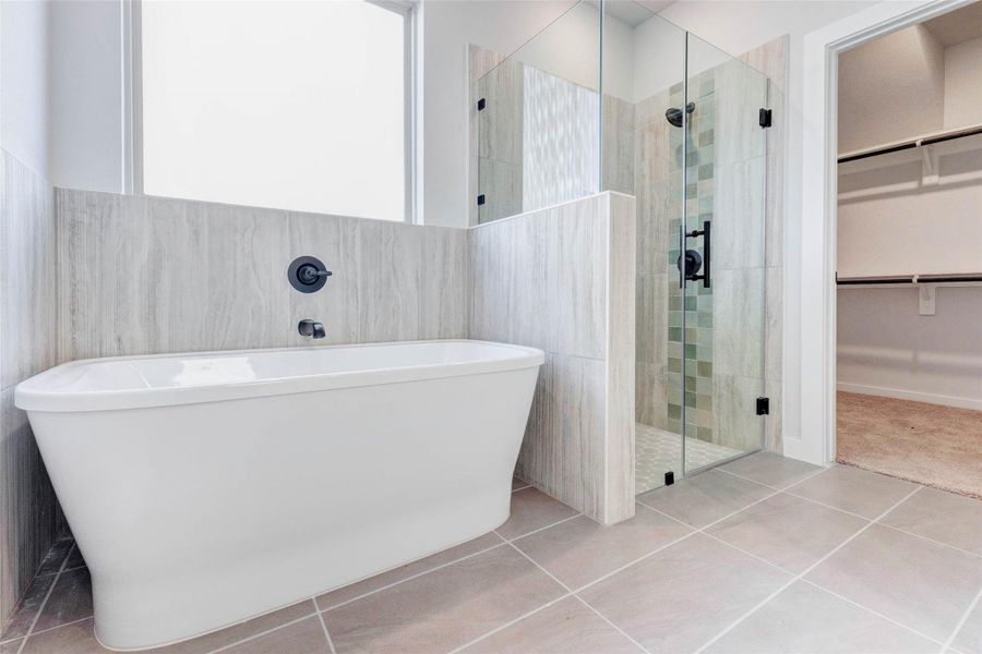 Indulge in the designer finishes of the primary bath, complete with a soaking tub beneath a large privacy window and a fully tiled walk-in shower with glass enclosure and accent tile. This space blends luxury and practicality beautifully.