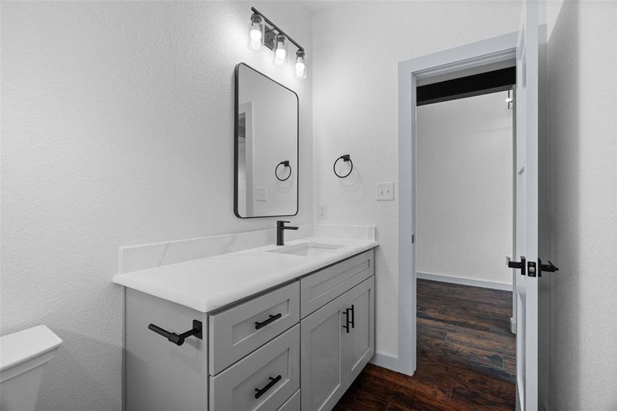 Bathroom with vanity, dark wood finished floors, and a textured wall