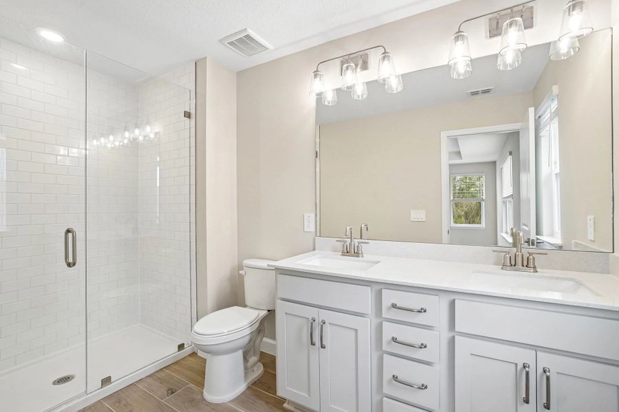 The primary bathroom features aspects of AW Collection® Milan and a frameless walk-in shower