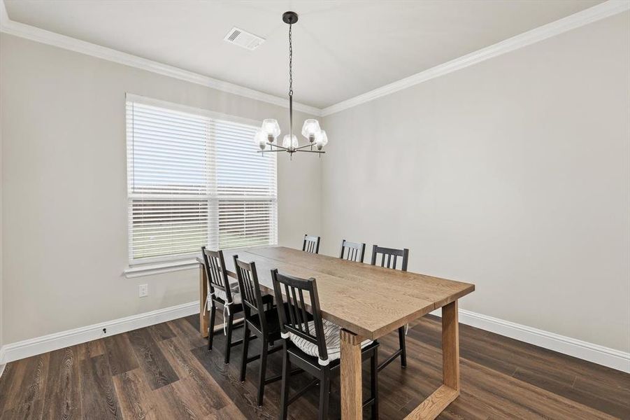 Dining area featuring ornamental molding, dark wood-style flooring, and a chandelier