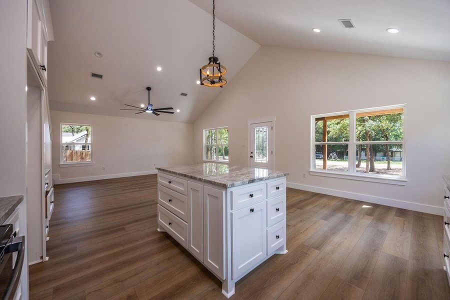 Kitchen featuring white cabinetry, decorative light fixtures, light stone countertops, dark wood-type flooring, and recessed lighting