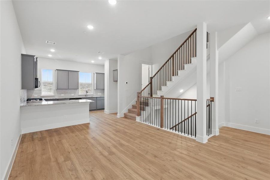 Kitchen with gray cabinetry, backsplash, light wood-style flooring, a peninsula, and recessed lighting