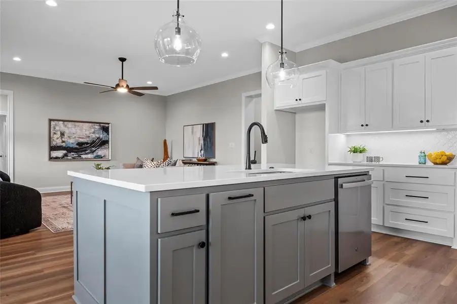 Kitchen with gray cabinetry, open floor plan, crown molding, white cabinetry, and a ceiling fan Kitchen with gray cabinetry, open floor plan, crown molding, white cabinetry, and a ceiling fan