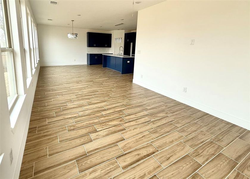 Unfurnished living room with a sink, baseboards, a wealth of natural light, and wood finish floors