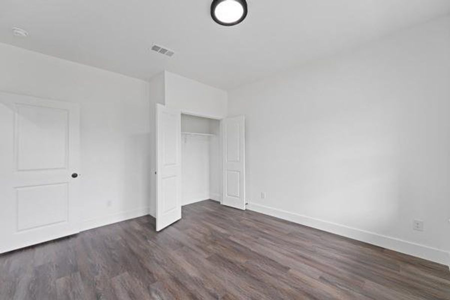 Bright room featuring wood-finish flooring, white walls, and a contemporary flush-mount ceiling light Bright room featuring wood-finish flooring, white walls, and a contemporary flush-mount ceiling light