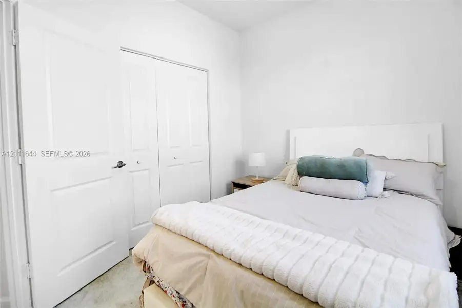 Neutral-toned interior featuring crisp white walls, a dual-panel closet with brushed nickel hardware, and high-pile wall-to-wall carpeting Neutral-toned interior featuring crisp white walls, a dual-panel closet with brushed nickel hardware, and high-pile wall-to-wall carpeting