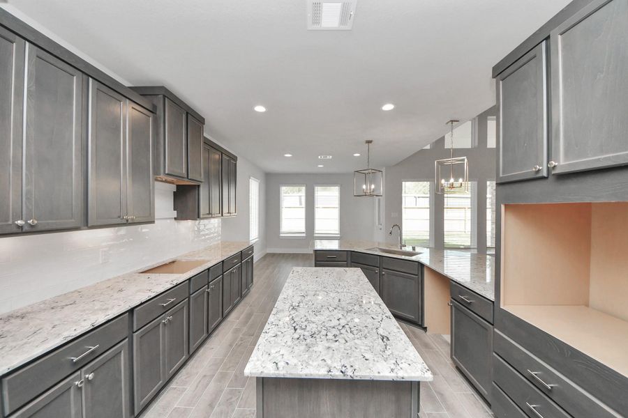The kitchen is a culinary haven, featuring granite countertops, a tile backsplash, stainless steel appliances, 42” upper cabinets, and undercabinet lighting.