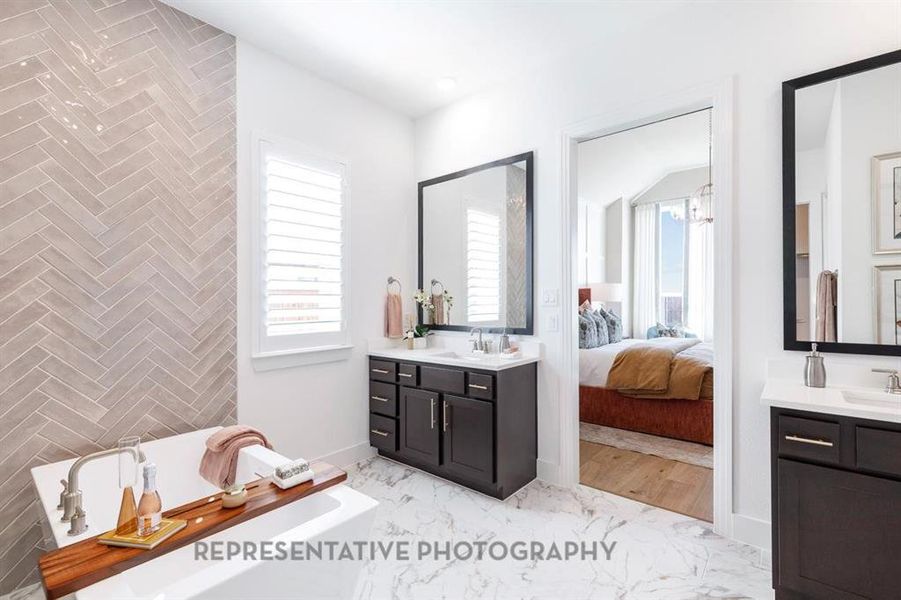 Bathroom featuring two vanities, a freestanding bath, and healthy amount of natural light